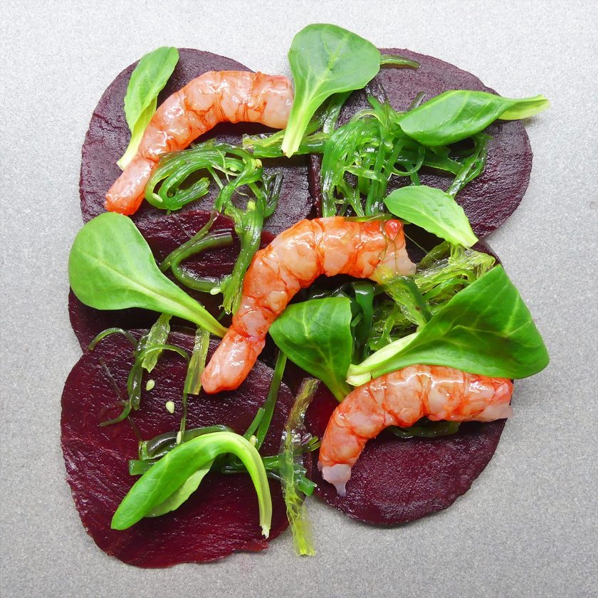 Prawns on slices of beetroot with lamb's lettuce and seaweed, from above