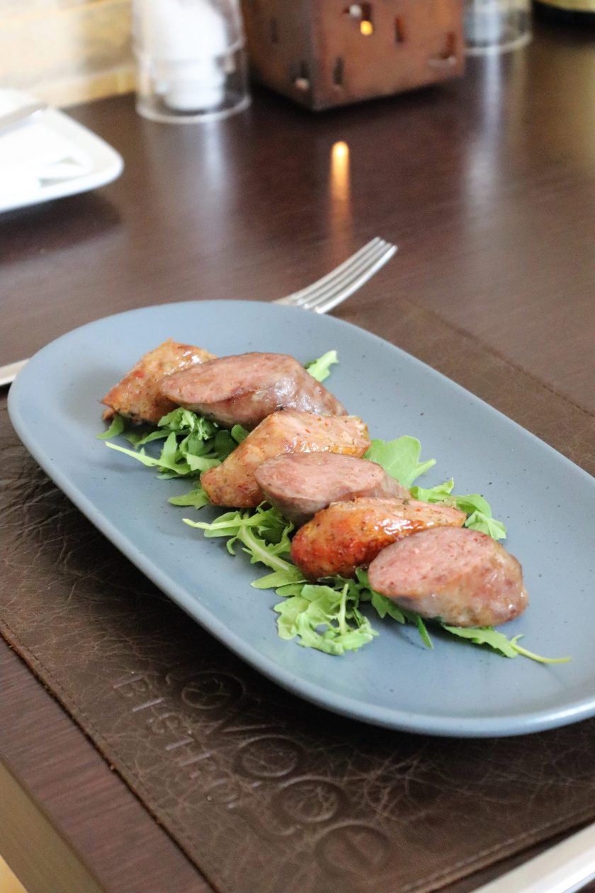 Slices of grilled sausage on rocket on a blue plate